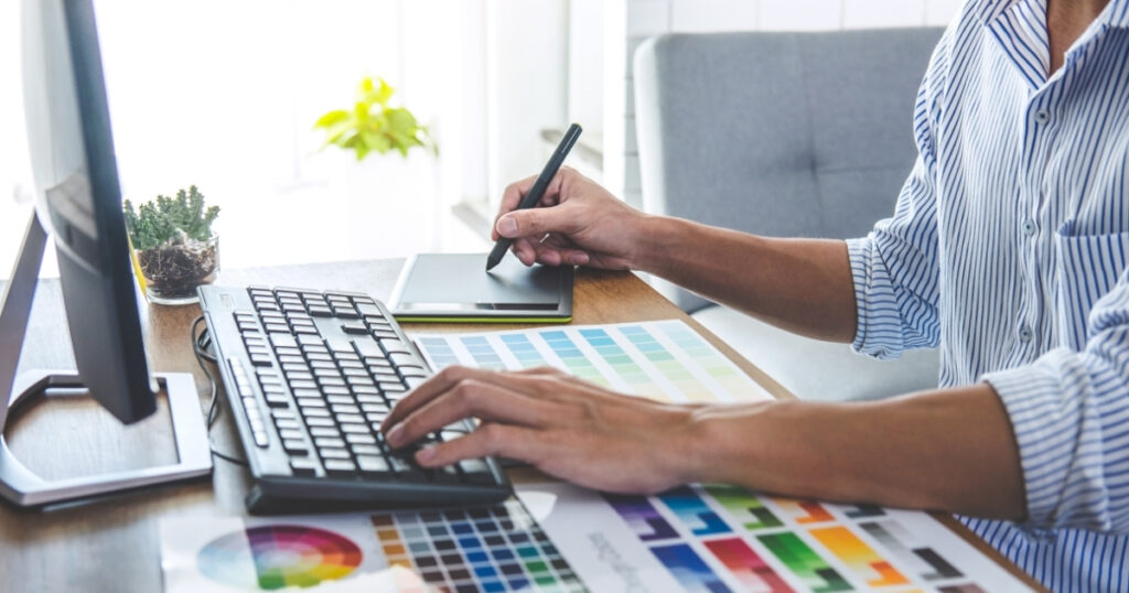 Flat lay of branding materials including color swatches, logo sketches, and a laptop — representing a brand identity refresh process.
