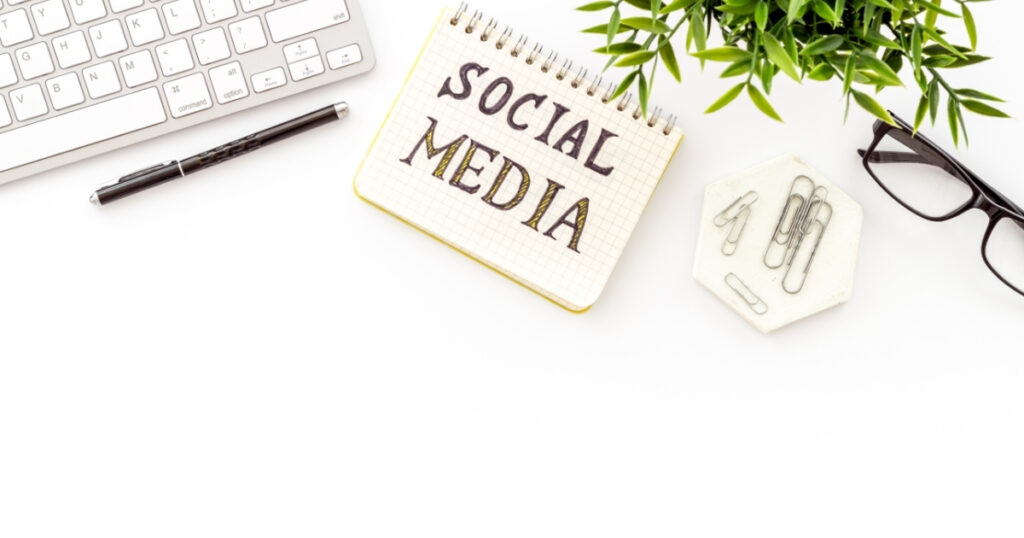 Workspace with notebook labeled social media, keyboard, and plant representing planning and strategy for social media trends in 2026.