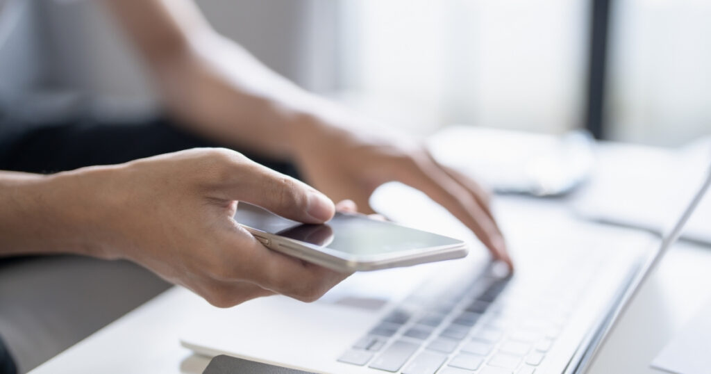 Person using smartphone and laptop representing social media search and digital marketing behaviour shift.